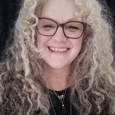 Susan Vinson, smiling, with long curly fair hair and glasses